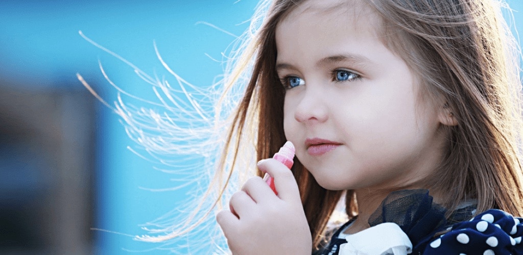 Little girl putting on lip balm