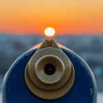 Photo of the lens end of a scope with a cityscape at sunset in the background