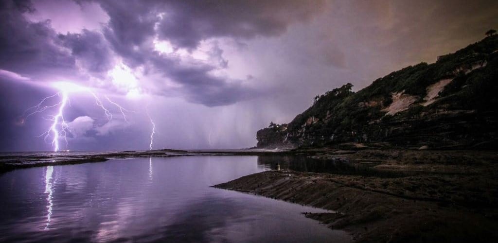 Photograph of a coastal scene with large dark clouds and lightning