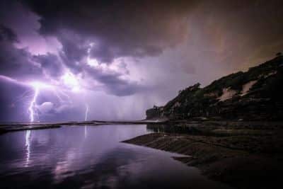 Photograph of a coastal scene with large dark clouds and lightning