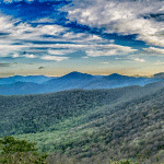 Image of rolling hillsides and a blue sky with fluffy clouds.